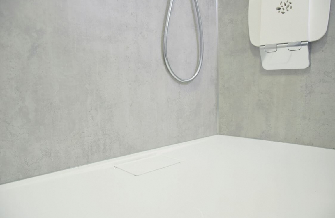 Fugenloses Sichtbeton Dekor in Dusche mit Brausetasse und Klappsitz